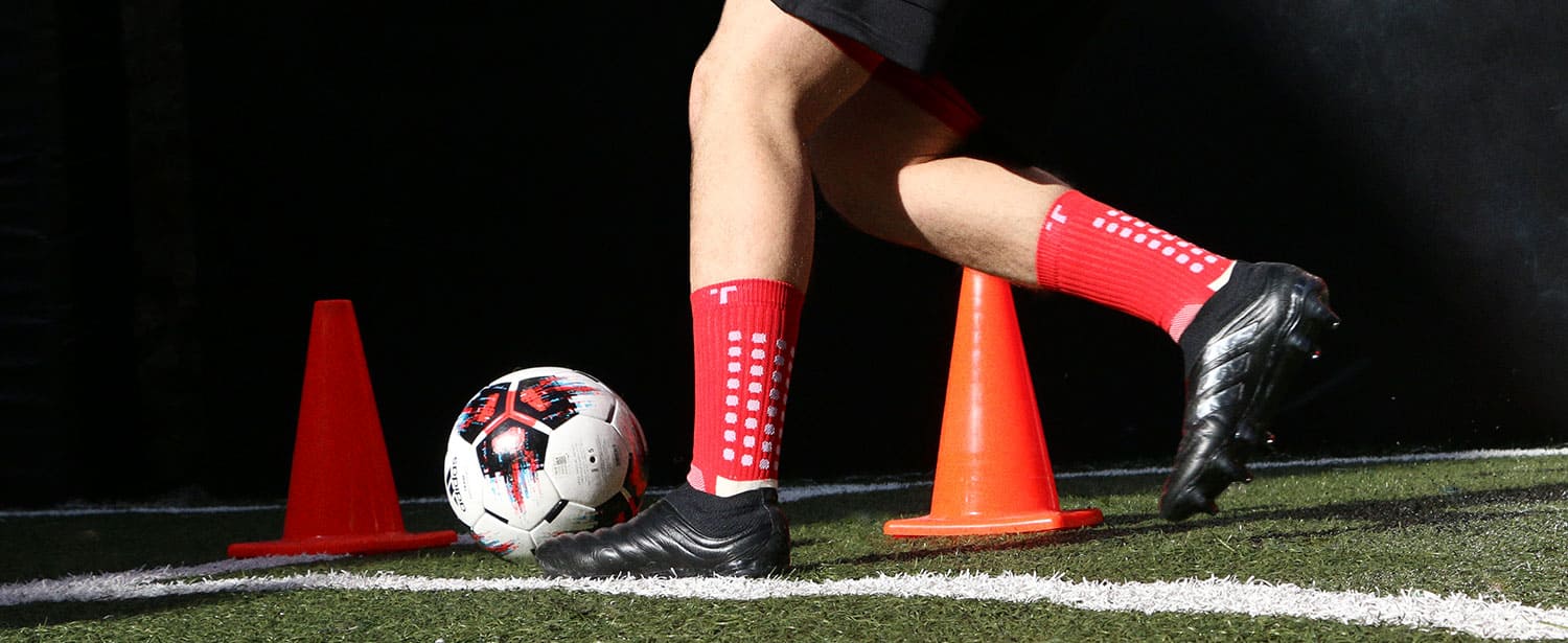 Jugador entrenando en el campo de fútbol con los calcetines Trusox de color rojo